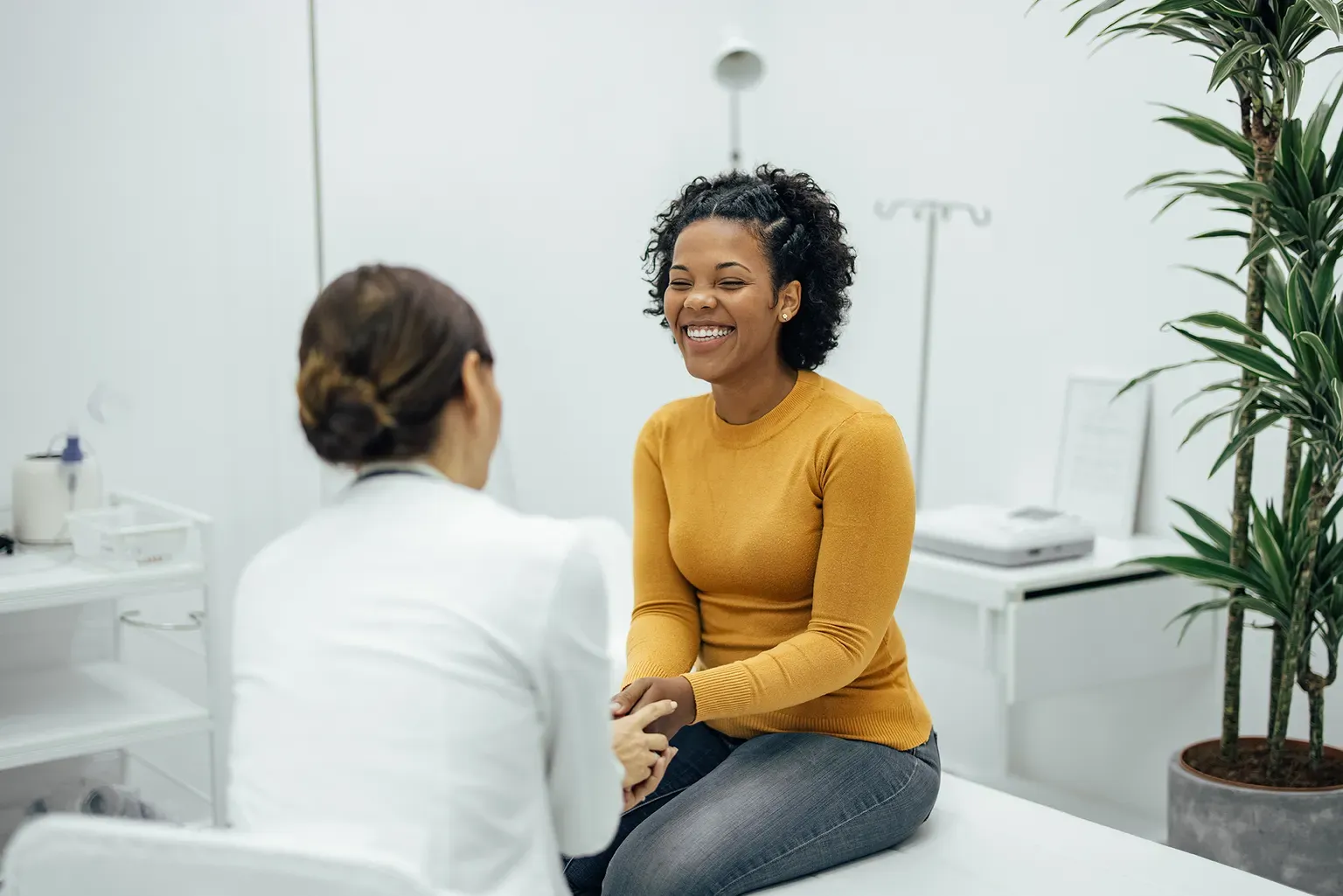 A woman sits on an exam table and talks to a nurse